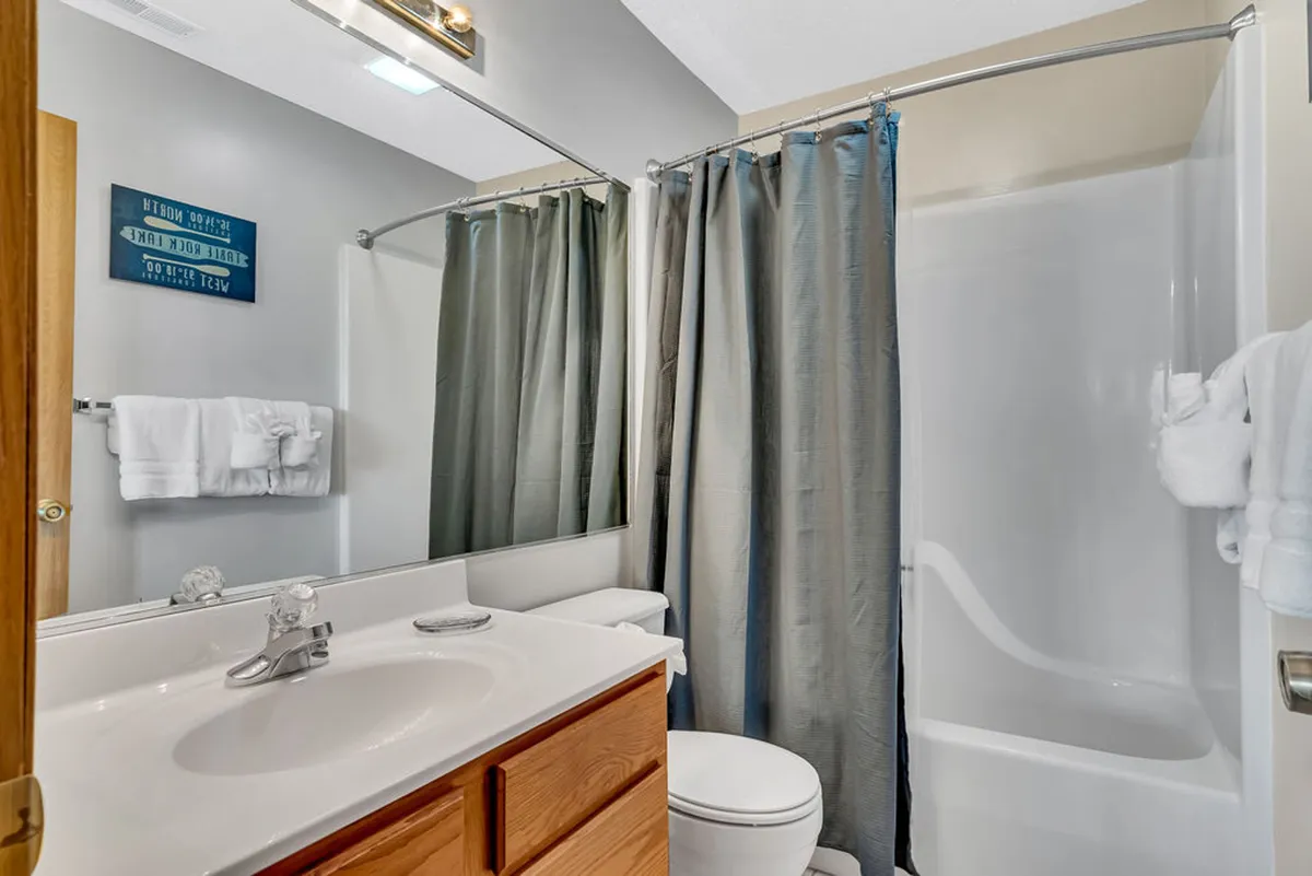 A modern, serene bathroom with a vanity sink, spacious mirror, a walk-in shower, and towel rack. The clean, contemporary design and soft lighting create an inviting setting for self-care and relaxation after a busy day.