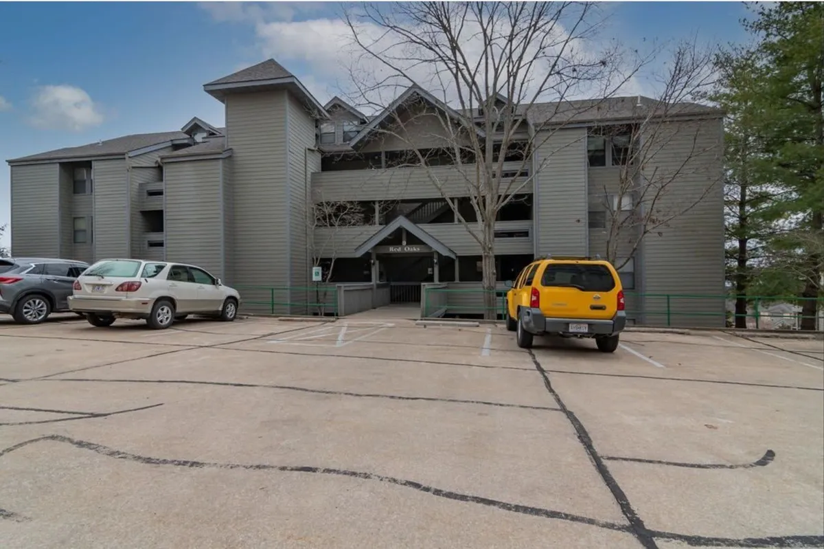 A welcoming apartment building with a spacious parking area in front and mature trees providing a touch of nature. The environment suggests a friendly and accessible community space.