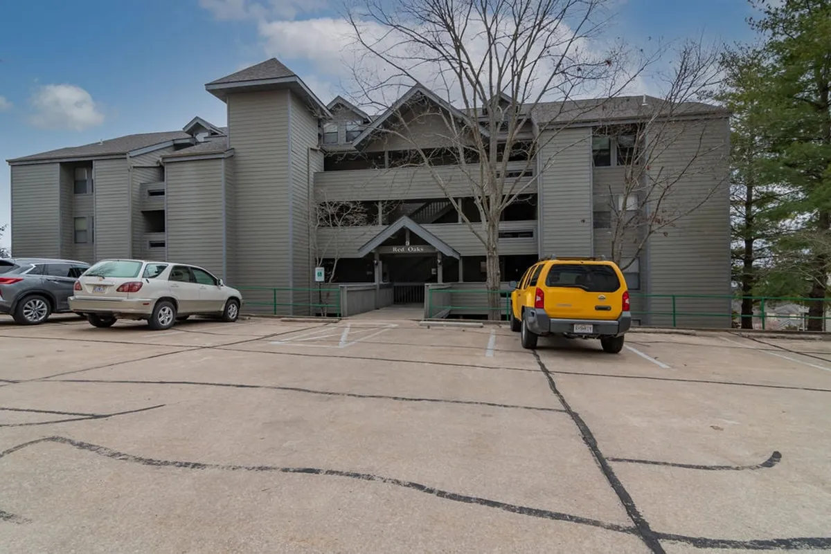 The exterior view of the building facade with a clearly marked parking area and trees in the background. The scene is bright and welcoming, emphasizing accessibility and convenience.