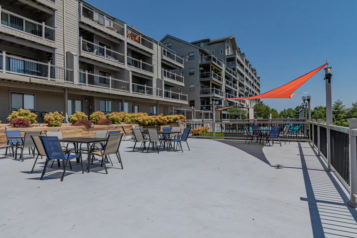 A charming outdoor seating area decorated with colorful planters and shaded by a sail, inviting guests to relax, share drinks, or enjoy a casual meal as the sun sets. The communal yet intimate vibe suits couples seeking peaceful moments together.