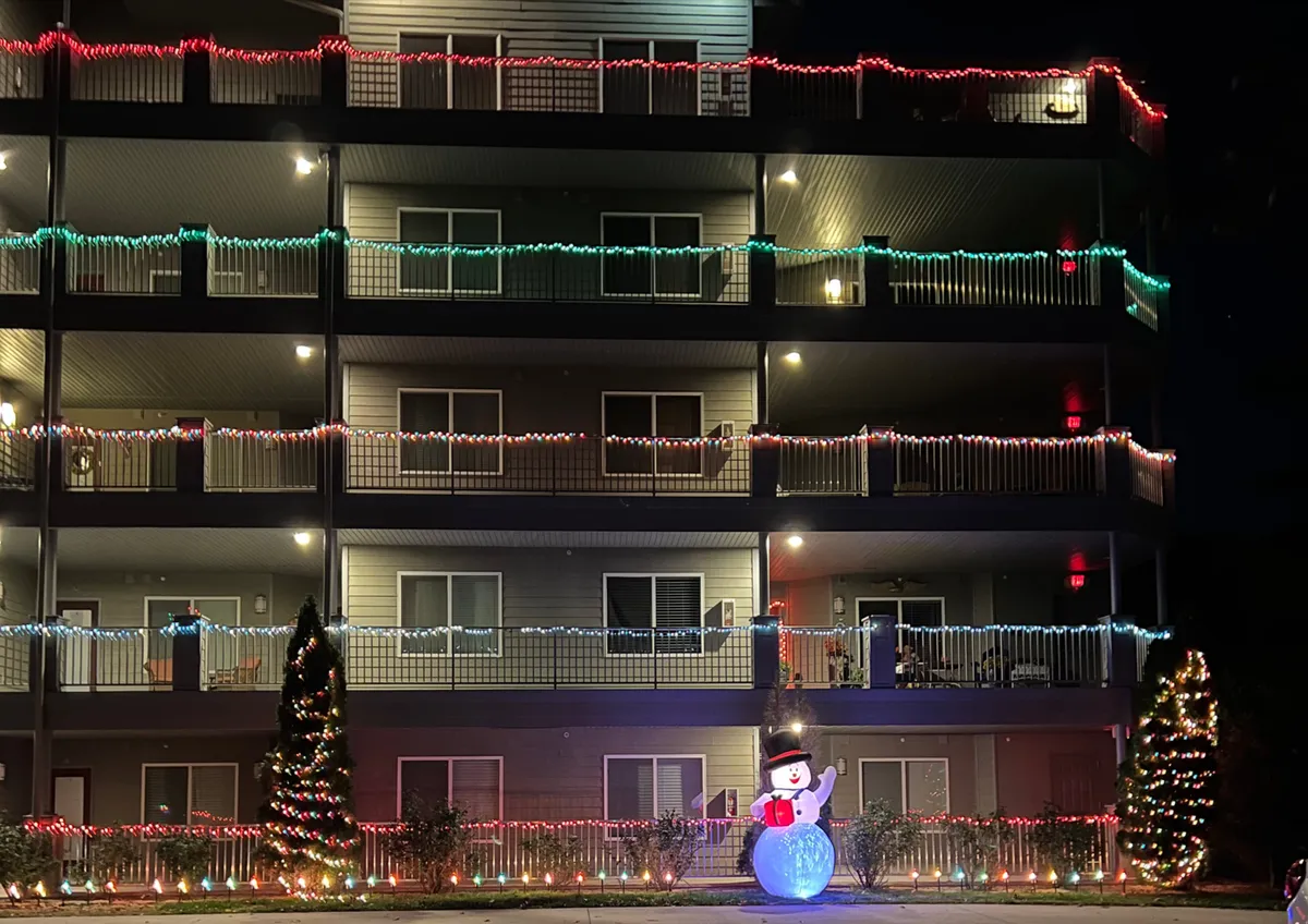 An exterior shot of the property decorated with holiday lights, a snowman decoration, and a Christmas tree. The festive atmosphere highlights the community feel and the joy of spending leisurely times in a scenic, welcoming environment. The exterior perspective showcases the property’s connection to the outdoors and its potential for memorable experiences year-round.