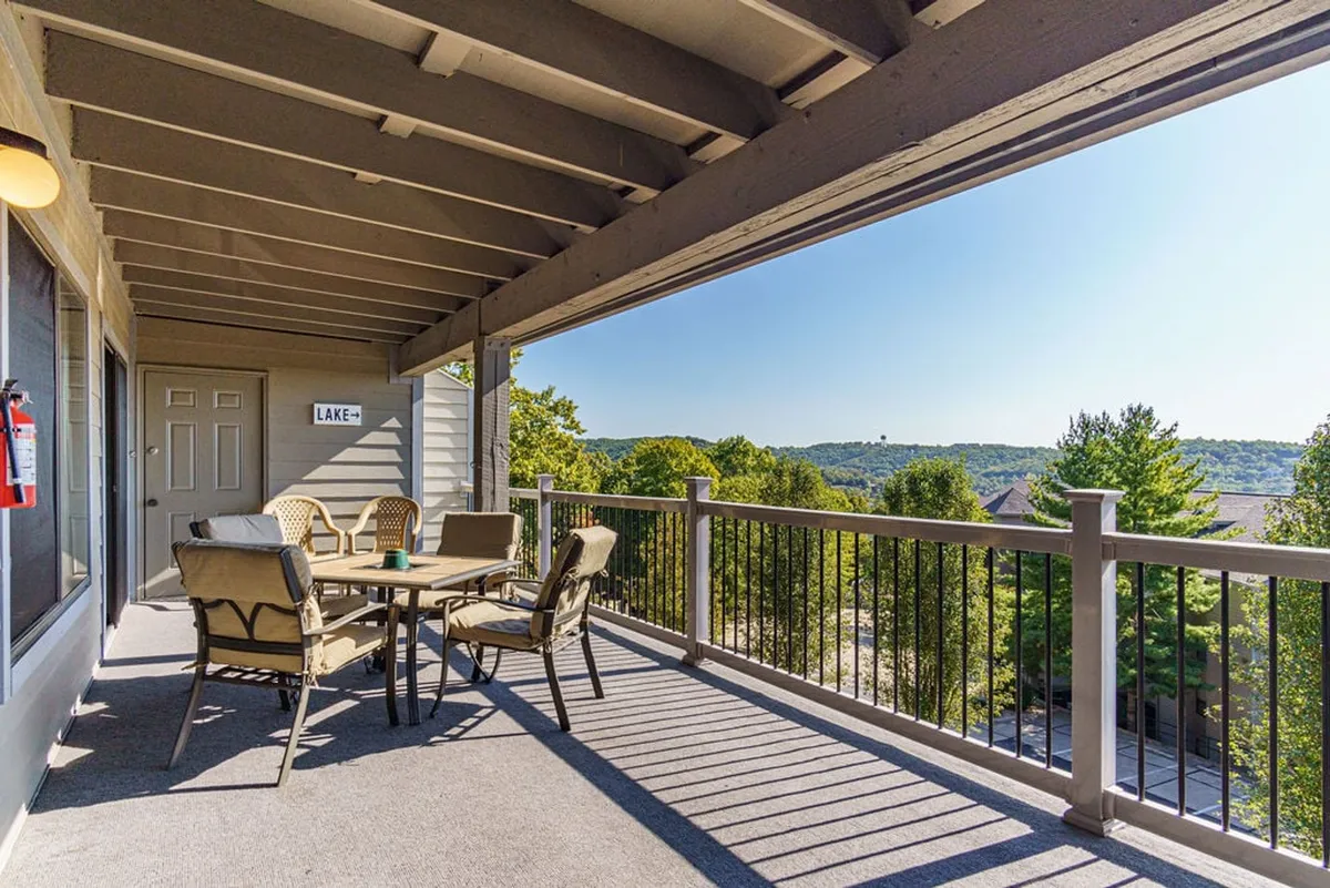 This image captures a spacious outdoor deck with a dining table, railings, and scenic views stretching beyond. The setting is tranquil, with the deck inviting guests to enjoy meals, relax, or gaze out at the landscape. The vantage point strongly suggests a seamless indoor-outdoor connection, aligning with the idea of the deck as an extension of living space.