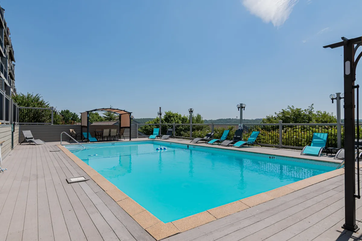 This image showcases an inviting outdoor swimming pool surrounded by lounge chairs and a canopy structure. The setting is perfect for unwinding, sunbathing, or enjoying a leisurely swim, and the ambiance is enhanced by natural light and open space.