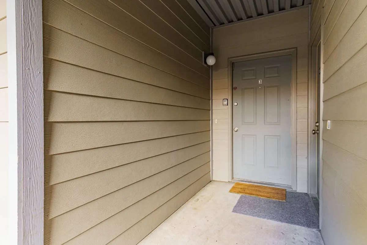 This image captures the front door of the condo, complete with a welcome mat and doorbell. The inviting entryway sets an immediate tone of comfort and hospitality, hinting at the restful experience within. The clean, accessible entrance also nods to the elevator access mentioned in the section, making it a relevant choice for seniors and retirees seeking ease and convenience.