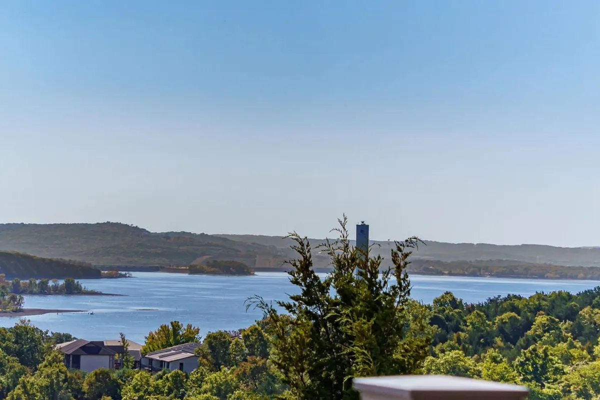 This image highlights the serene expanse of Table Rock Lake, framed by trees and distant hills. The tranquil water and natural scenery evoke the peaceful atmosphere described in the narrative, with a hint of sunrise or sunset lighting. There’s a strong sense of quietude and rejuvenation inherent in the scene.